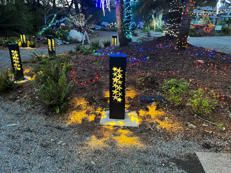 Lit Bollards With Starfish Cutouts At Dusk By Multicolored Lights